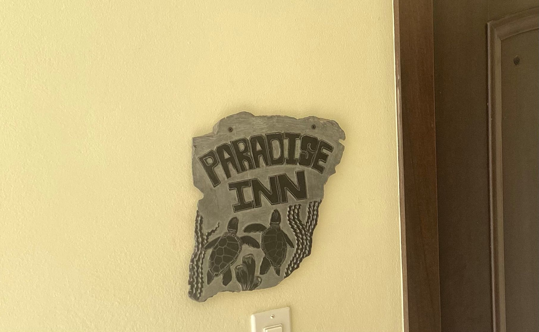 Wall sign on a yellow hallway wall reading “Paradise Inn” with a turtle graphic.