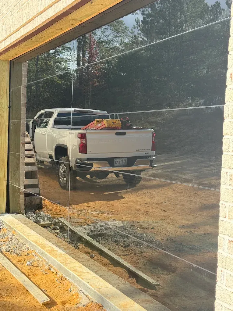 White pickup truck parked outside a storefront, reflected in a large window.