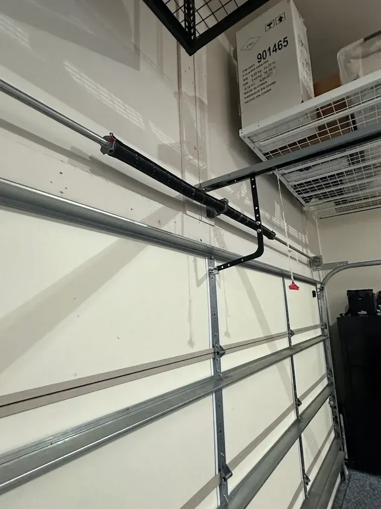 Garage wall with horizontal metal tracks and black support arms beneath storage shelves