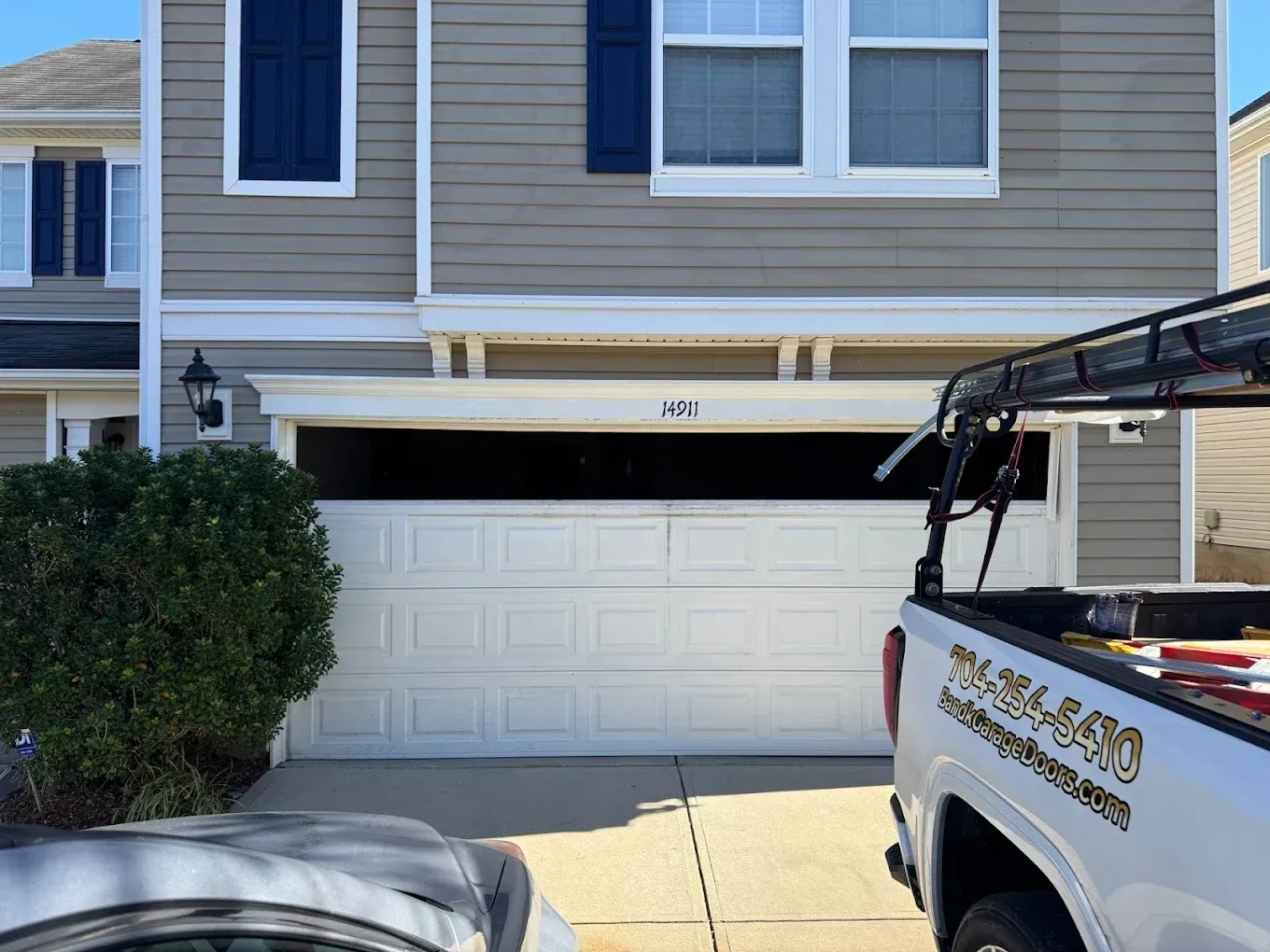 Suburban townhouse garage with white door, beige siding, and a pickup truck parked in front