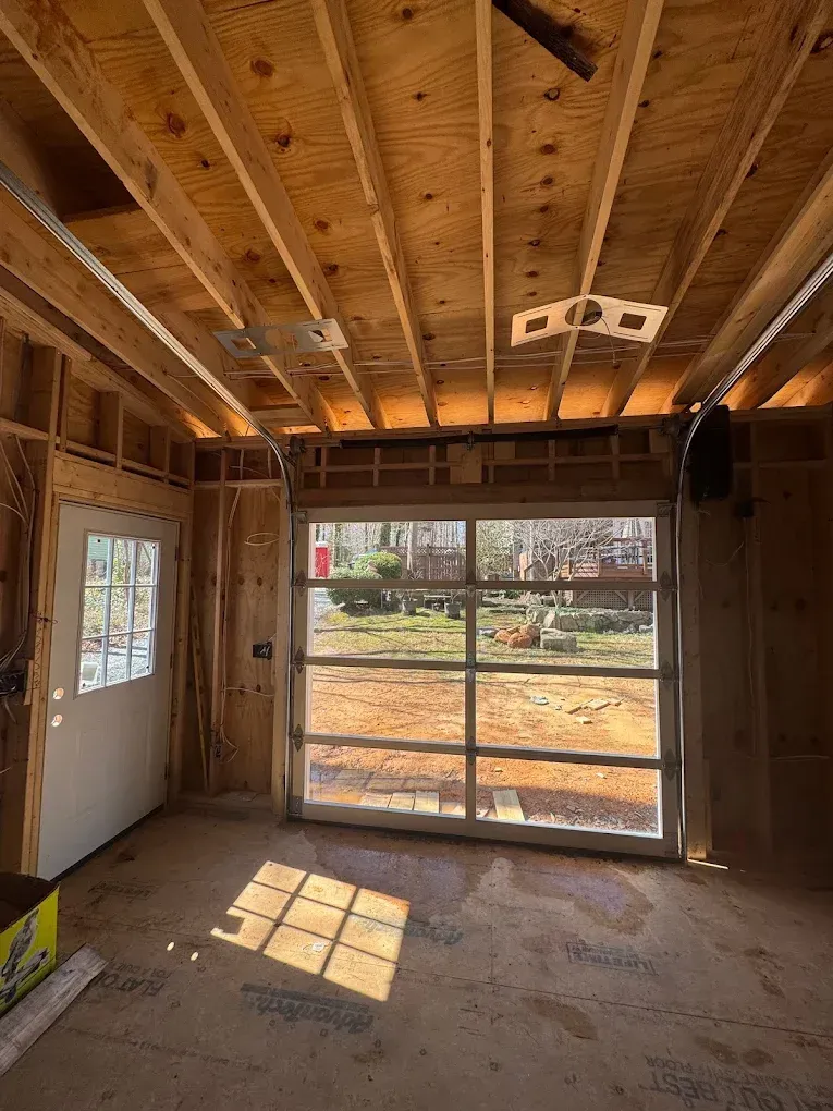 Unfinished room with exposed wood framing, window, and sunlight on the concrete floor