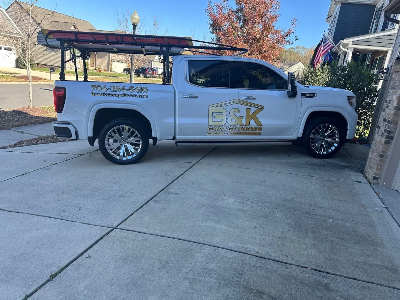 White pickup truck with gold decals parked in a driveway beside a brick house
