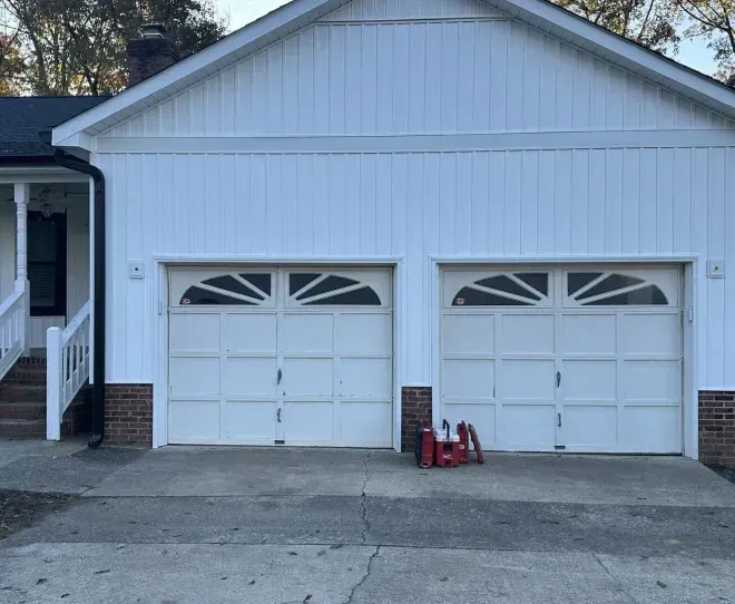 White two-car garage with two white doors and a red lawn mower on the driveway