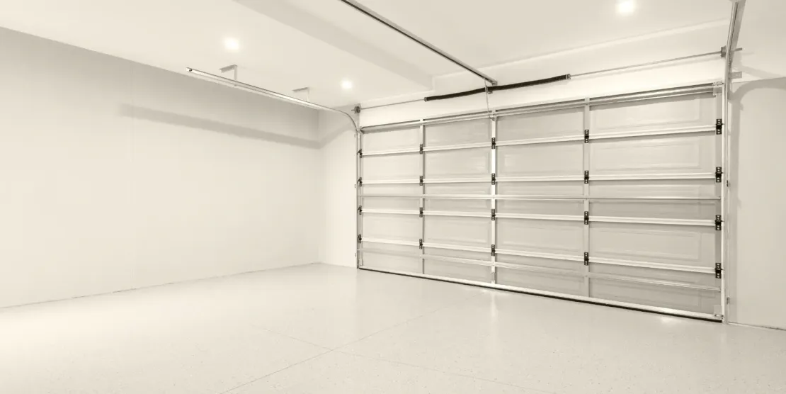 Empty white garage with metal storage racks on the right wall and bright overhead lights