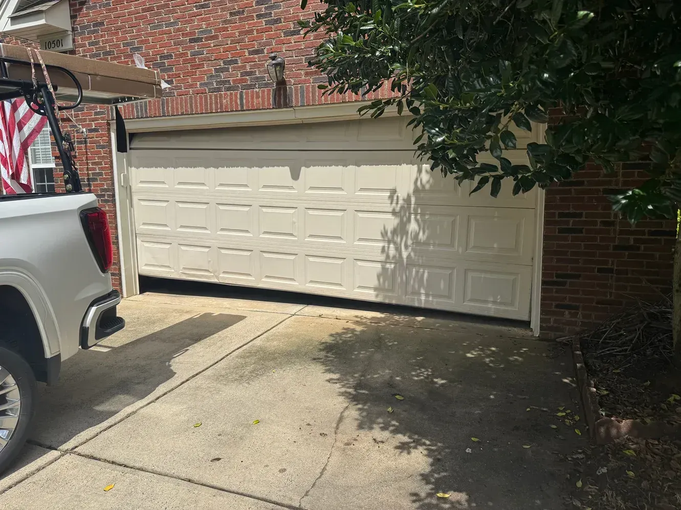 White double garage door on a brick house with a truck parked at the left edge of a driveway