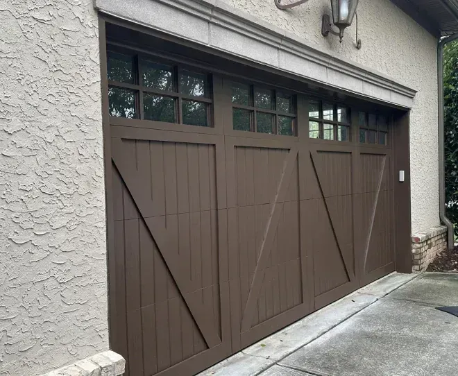 Brown garage doors on a stucco building beside a concrete driveway.