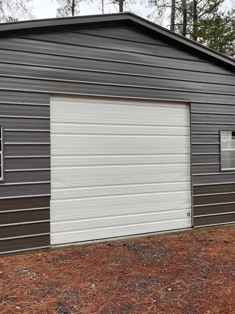 Dark gray building exterior with a large white garage door and small side windows