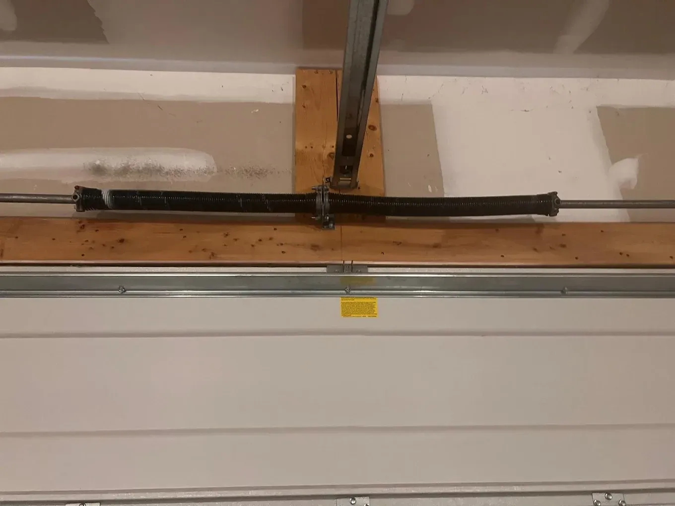 Garage door opener mechanism mounted on a garage ceiling above a white door
