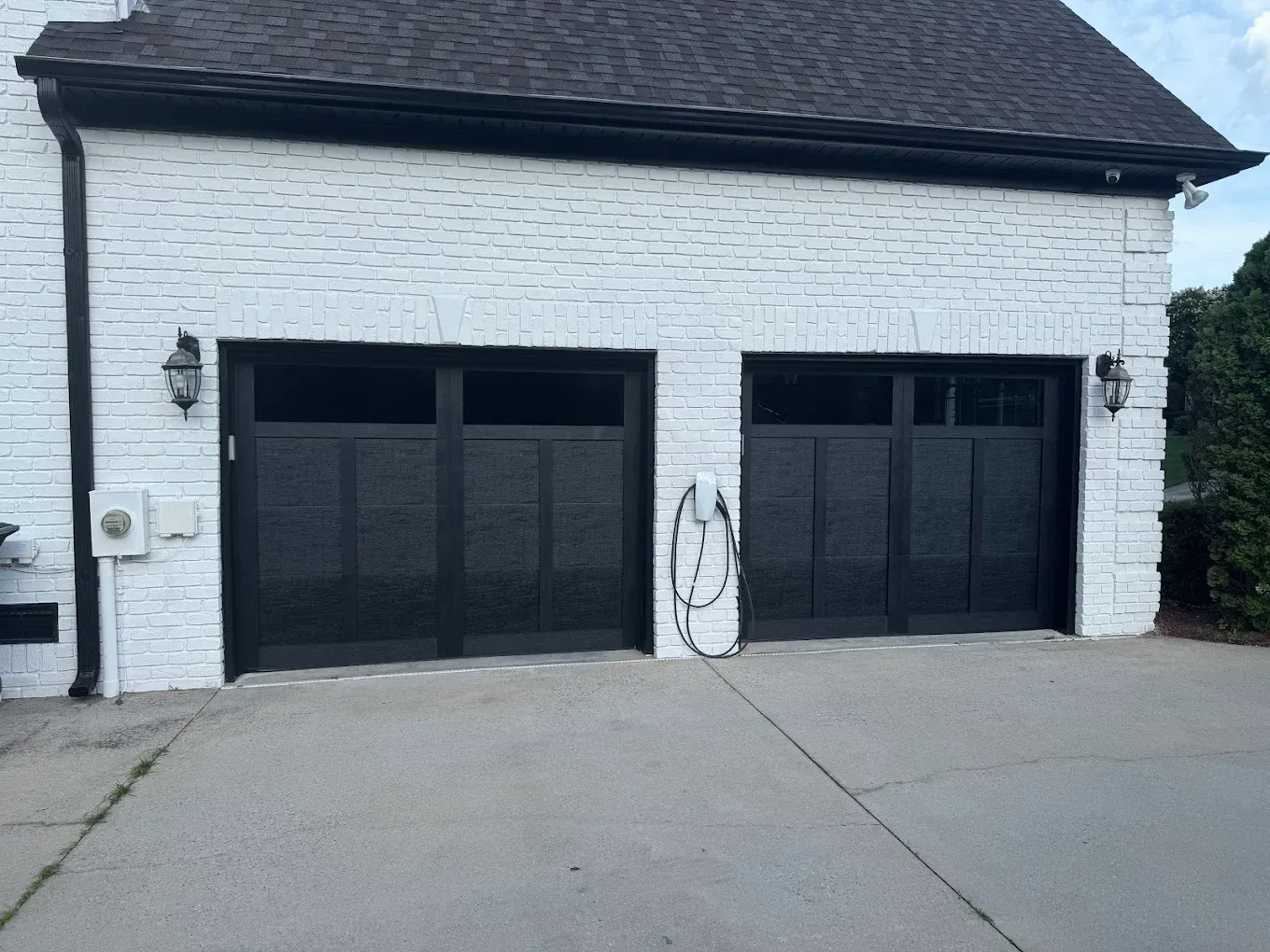 White brick house with two black garage doors and a concrete driveway
