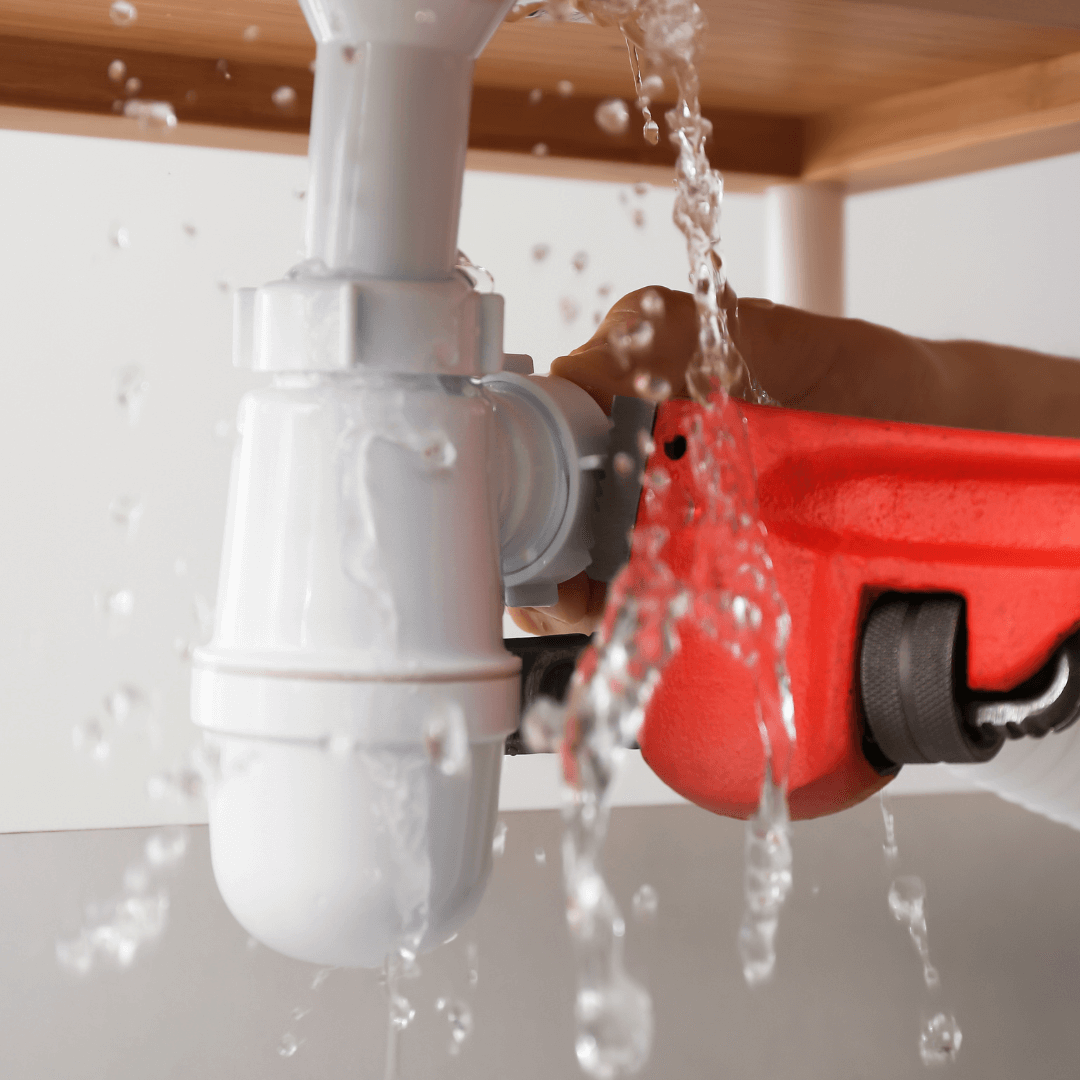 A person is fixing a sink that is leaking water
