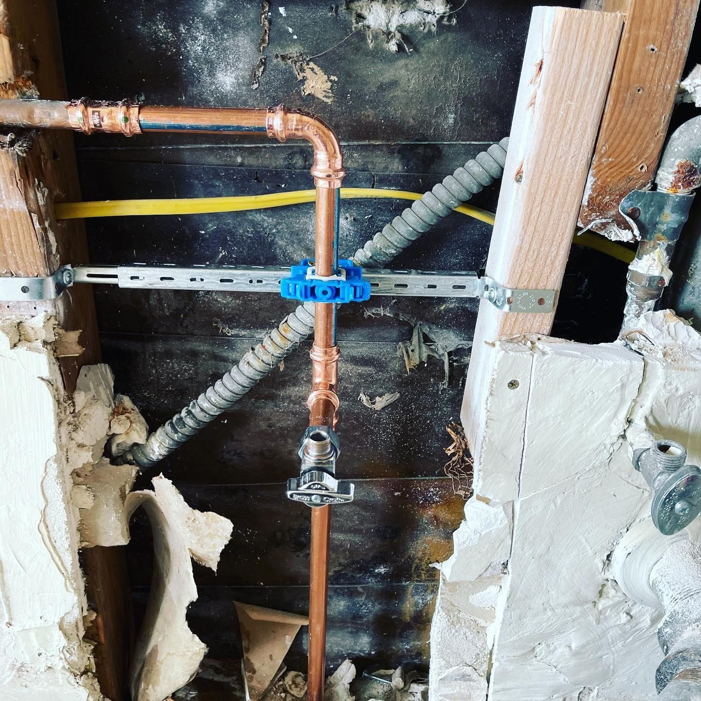 A copper pipe is being installed in a hole in a wall.