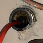A red hose is coming out of a hole in a wall.