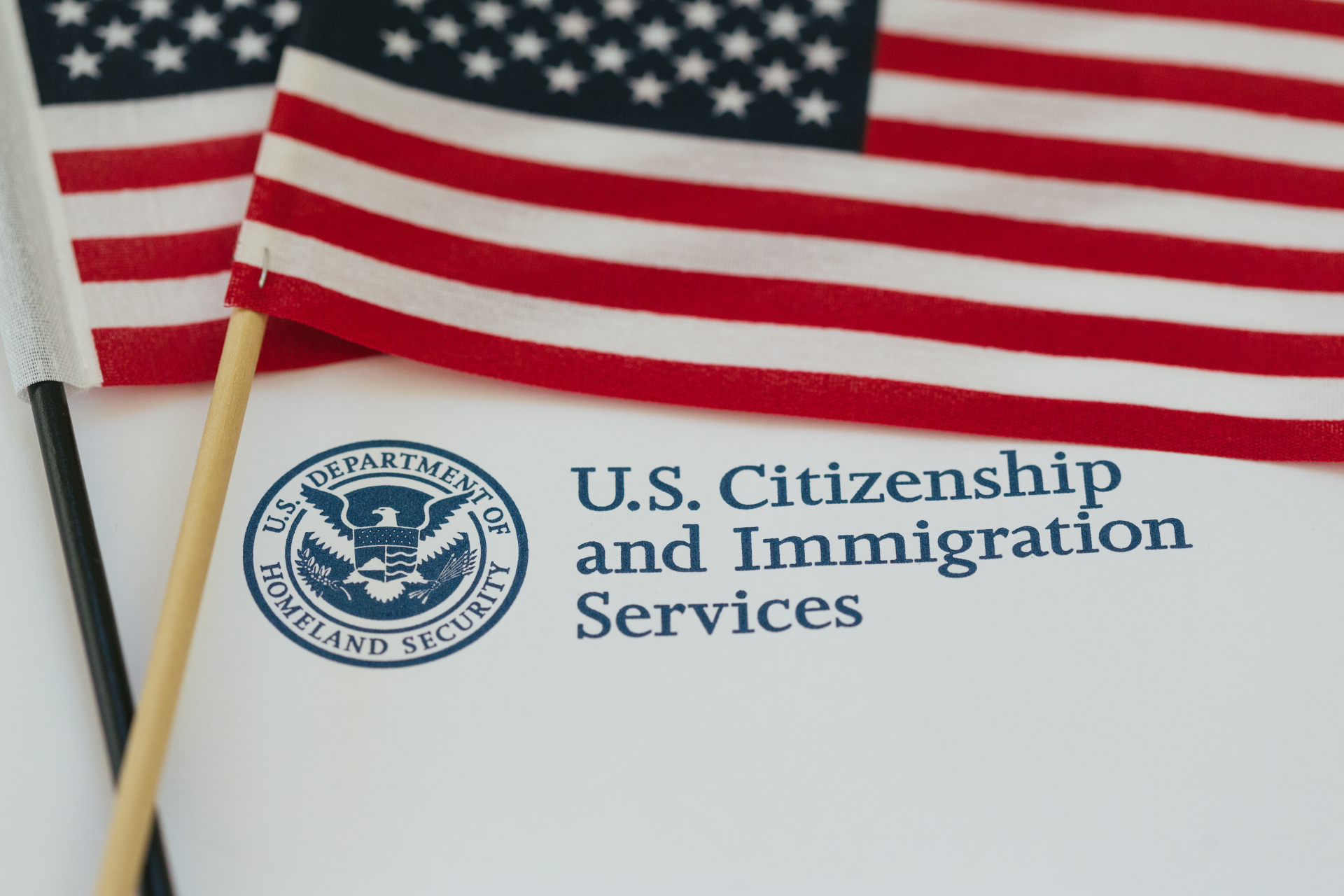Two american flags are sitting on top of a u.s. citizenship and immigration services envelope.