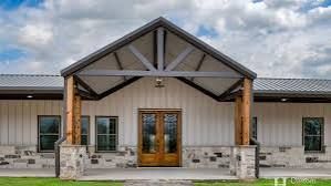 Farmhouse exterior with wooden entry porch, grey roof, and stone base.