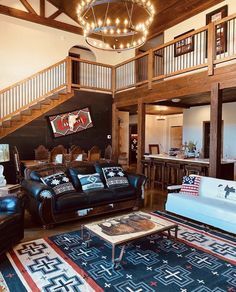 Living room with sofa, rug, and staircase, with a chandelier hanging above.