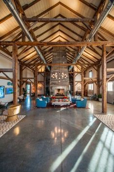 Spacious interior with exposed wooden beams, a fireplace, and blue armchairs.