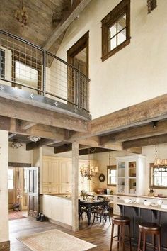 Rustic interior with exposed beams, loft, and kitchen with bar stools.