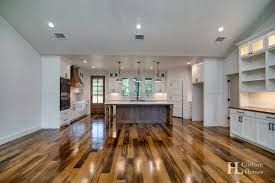 Spacious kitchen with a large island, wood floors, white cabinets, and recessed lighting.