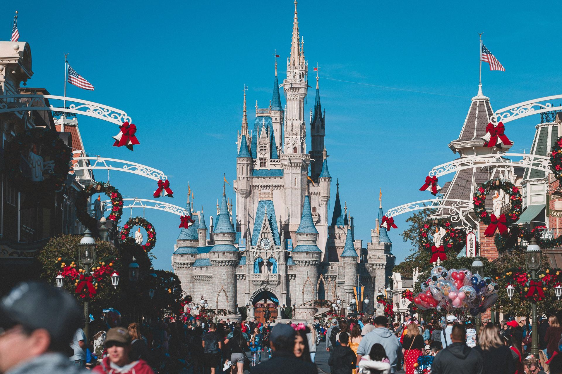 A crowded Main Street leads to the tall, light-colored Cinderella Castle at Disney World, decorated for the holidays.