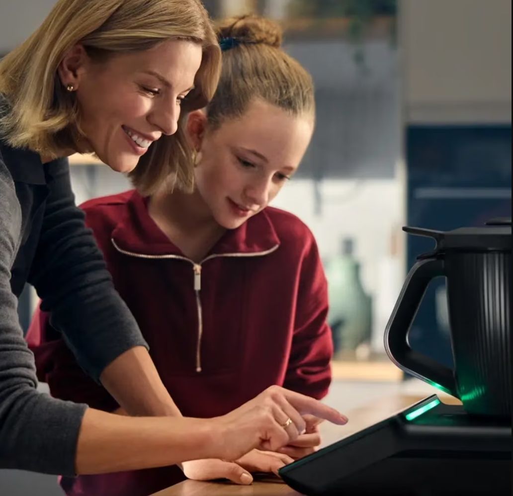 People Leaning Over a Appliances and Smiling in a Bright Kitchen — Clare Quintieri Thermomix Consultant in Mareeba, QLD