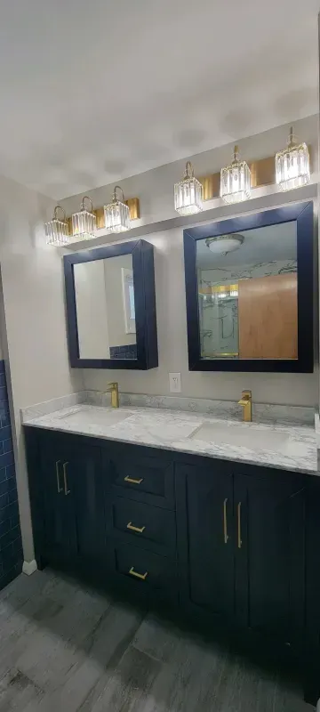 Modern bathroom vanity with double mirrors, marble countertop, dark cabinets, and wall sconces