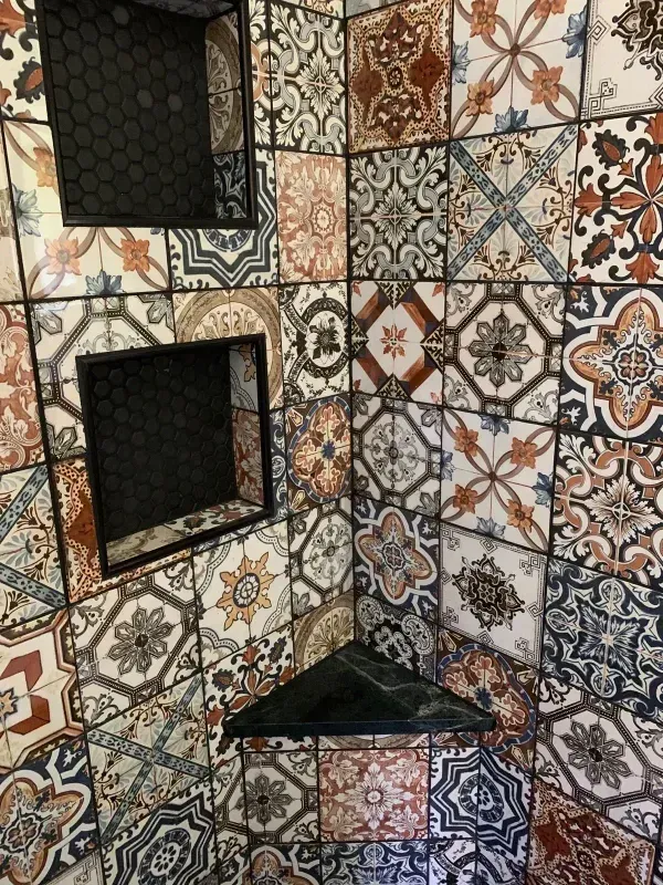 Decorative patterned tile wall with two recessed niches and a small corner shelf