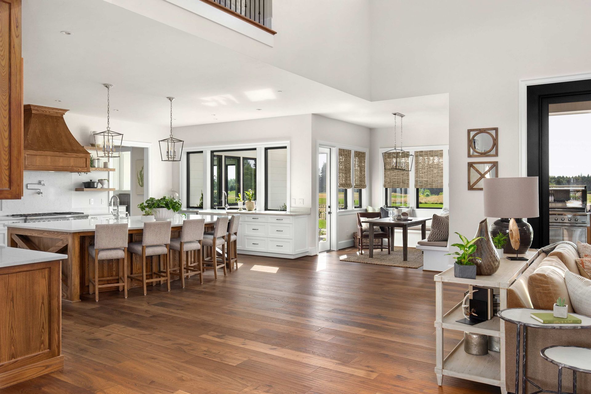 Bright open-concept kitchen and living room with hardwood floors, white cabinets, and large windows Bright open-concept kitchen and living room with hardwood floors, white cabinets, and large windows
