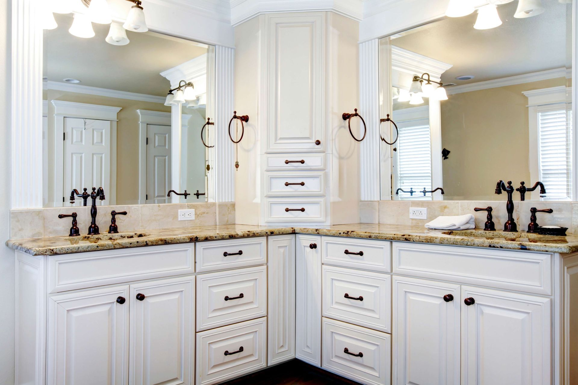 Elegant white bathroom vanity with double mirrors, gold countertops, and black faucets