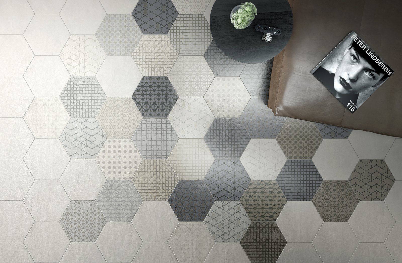 Hexagon-patterned floor with a black table, a potted plant, and a framed photo on a brown surface.