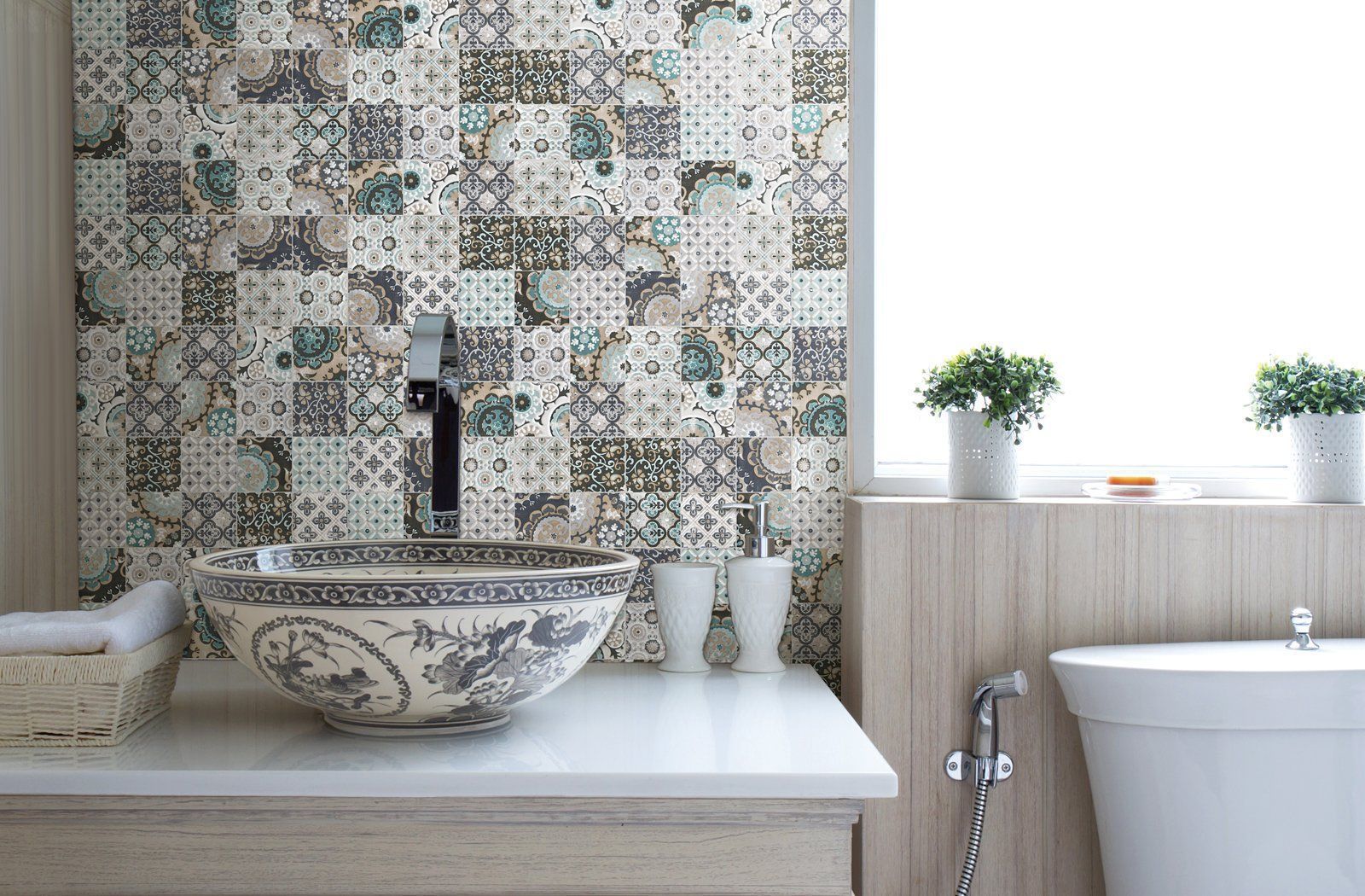 Modern bathroom with mosaic tile wall, stone sink, and white bathtub with plants on the ledge