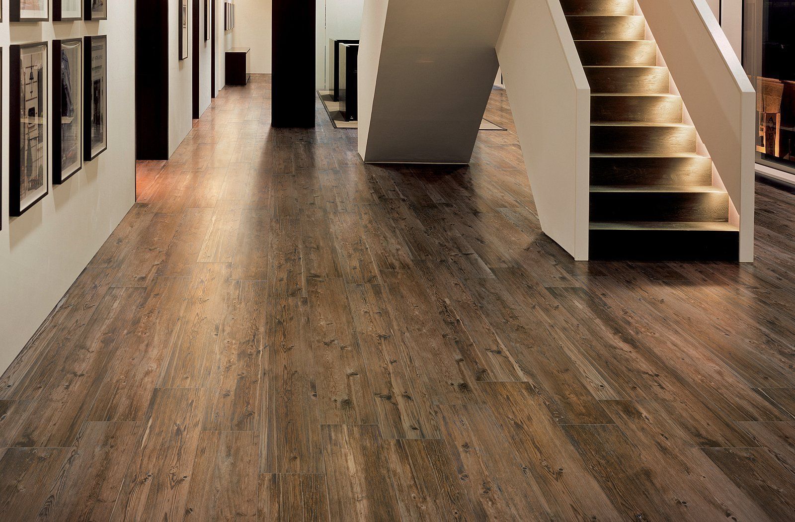 Hallway with wood flooring, framed wall art, and a staircase on the right.