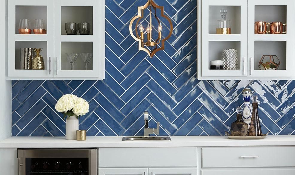 Blue herringbone tile wall with white cabinets, open shelves, and kitchen decor above a counter