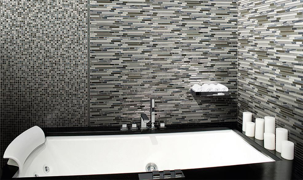 Modern bathroom with tiled walls, a freestanding tub, and candles on the right side.