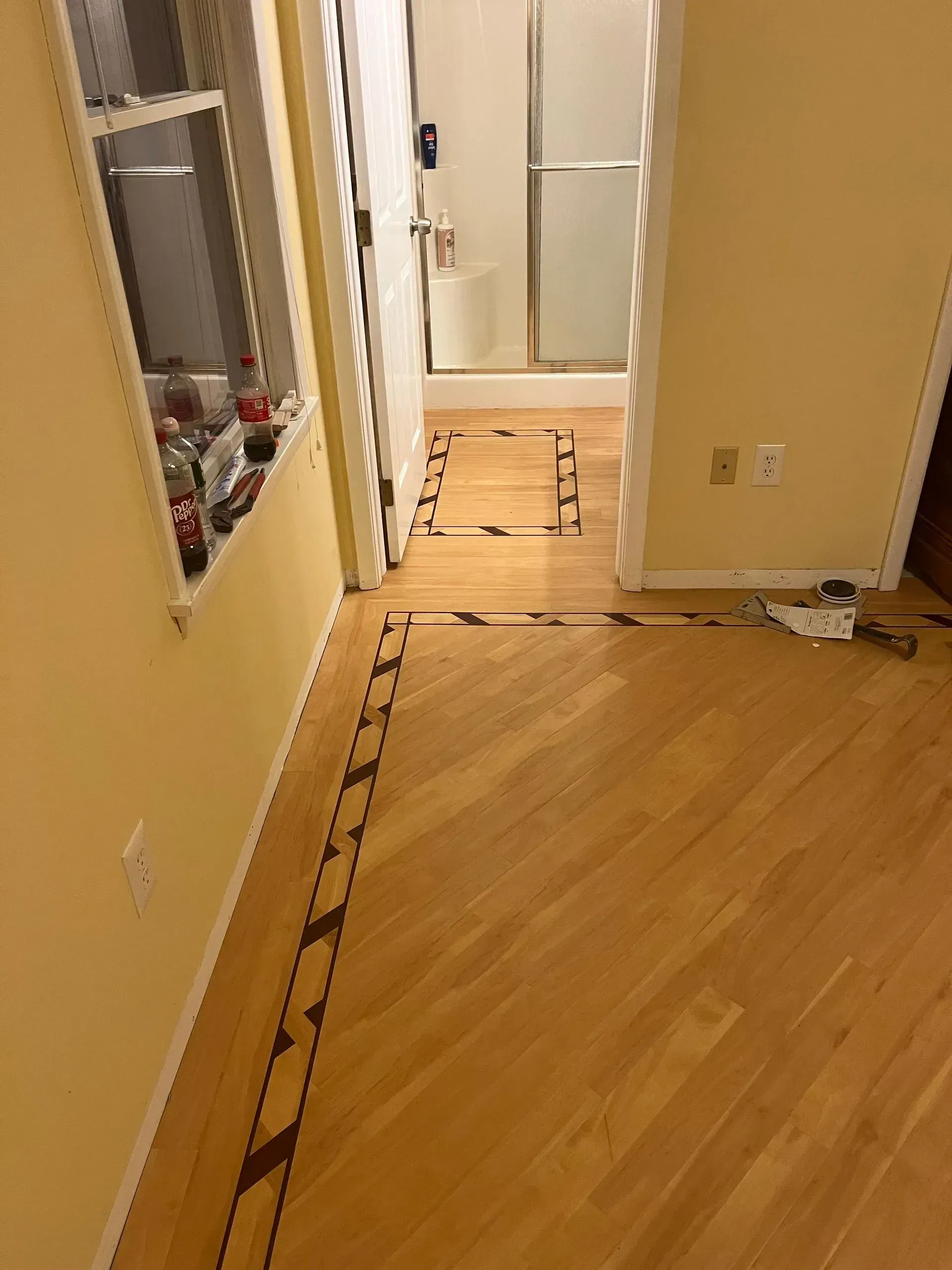Hallway with light wood floor, yellow walls, and a doorway with caution tape blocking part of the path