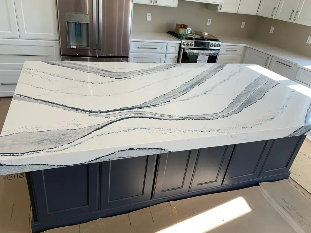 Kitchen island with white and gray veined marble countertop in a bright modern kitchen