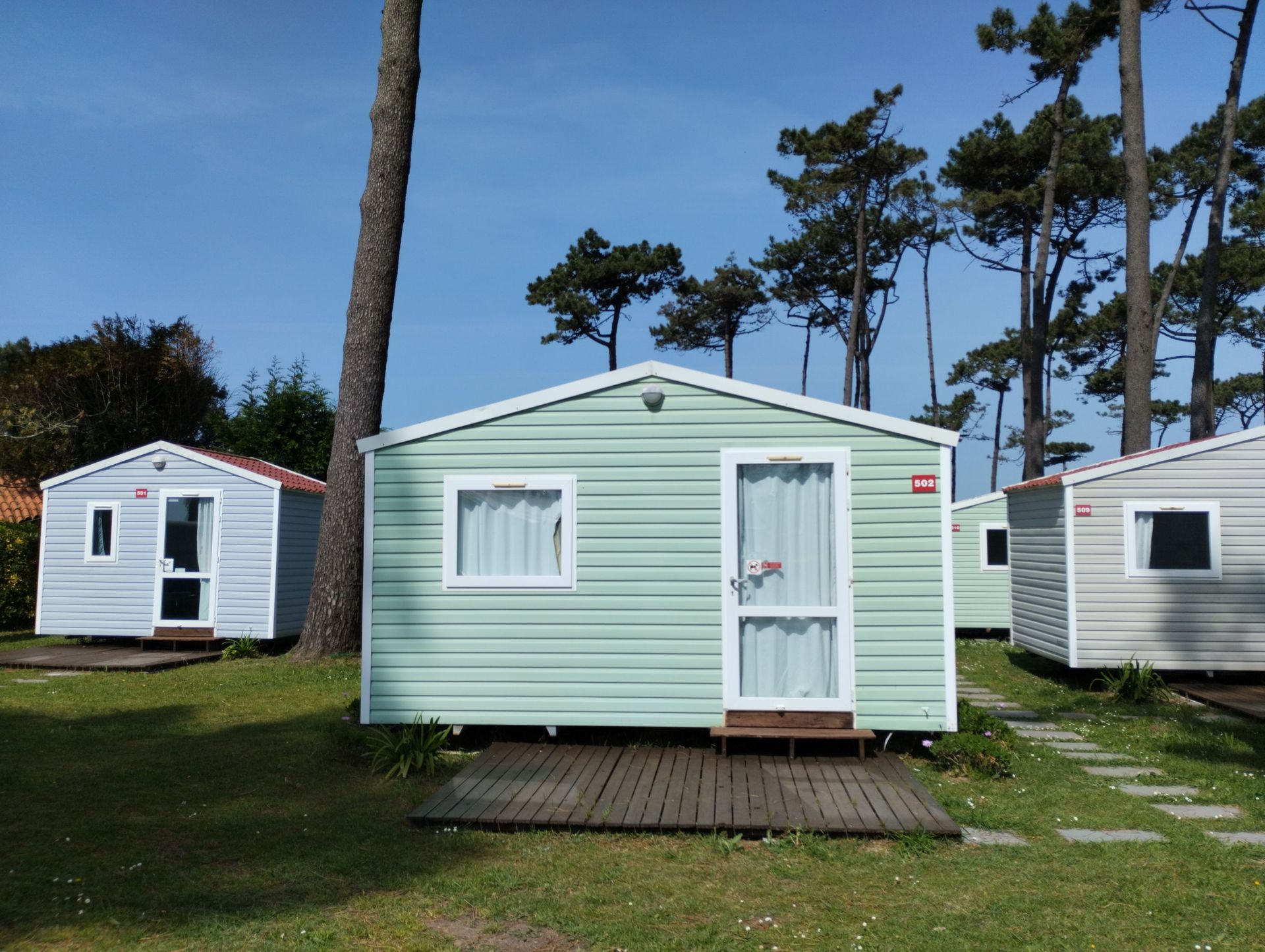 Small pastel mobile home on grassy ground under a blue sky