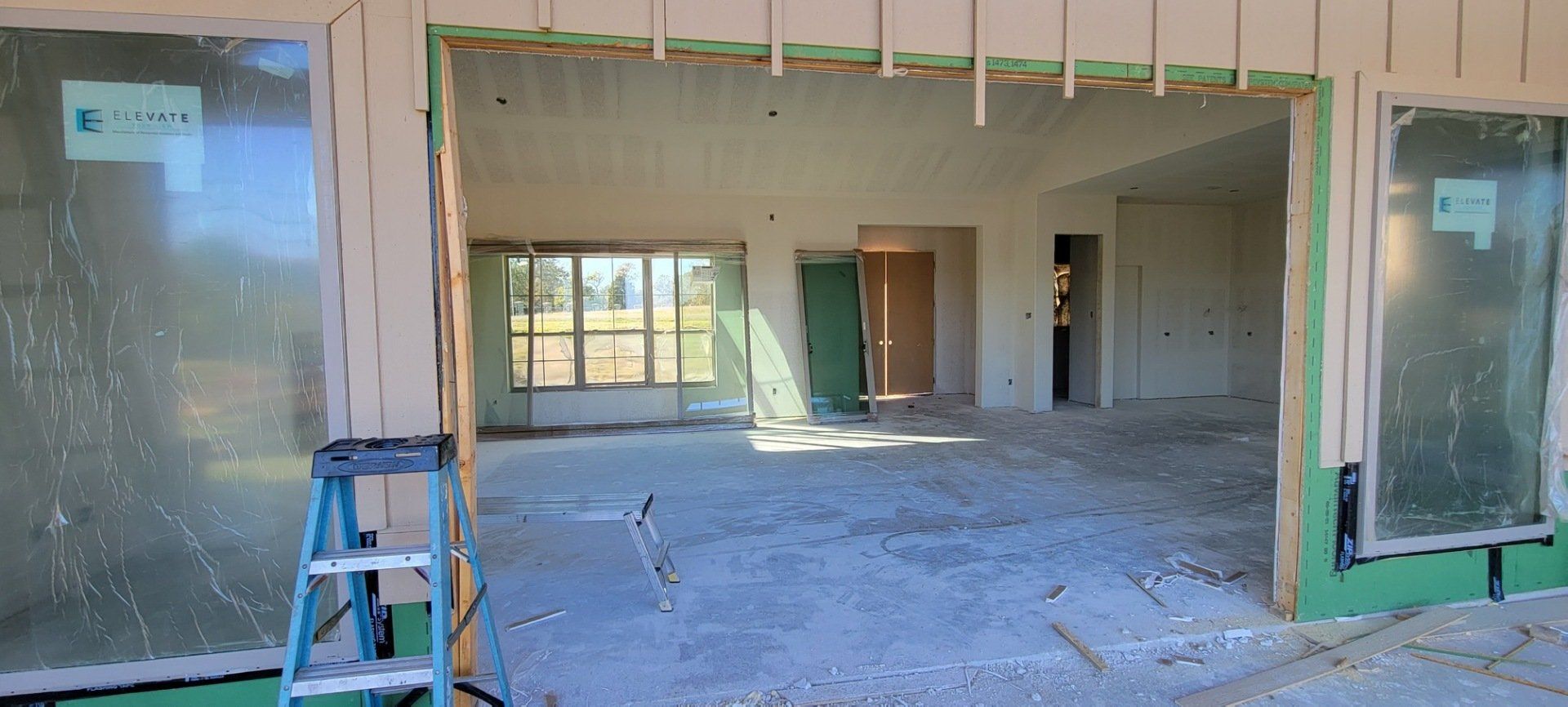 Partially finished building interior with open doorway and construction ladder in front