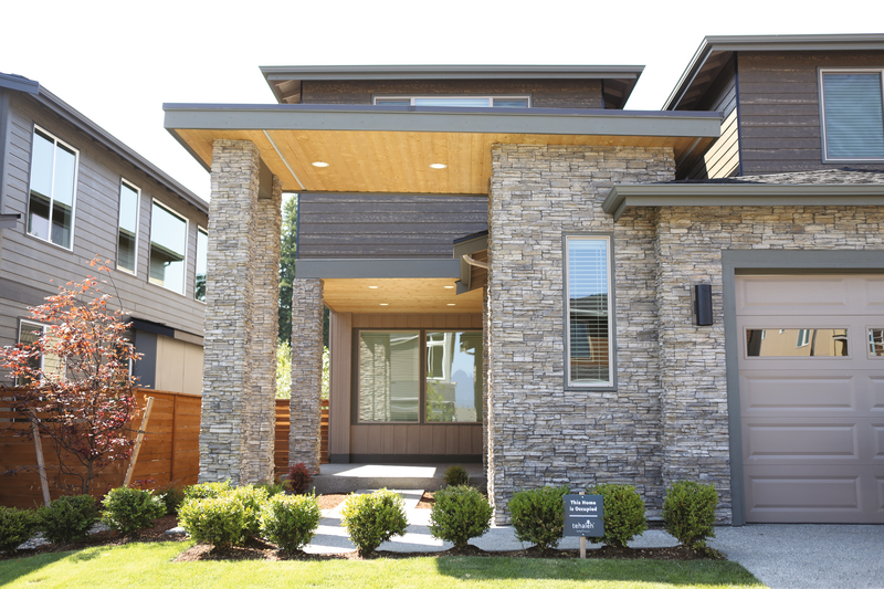 Modern two-story house with stone facade, wood accents, front lawn, and attached garage