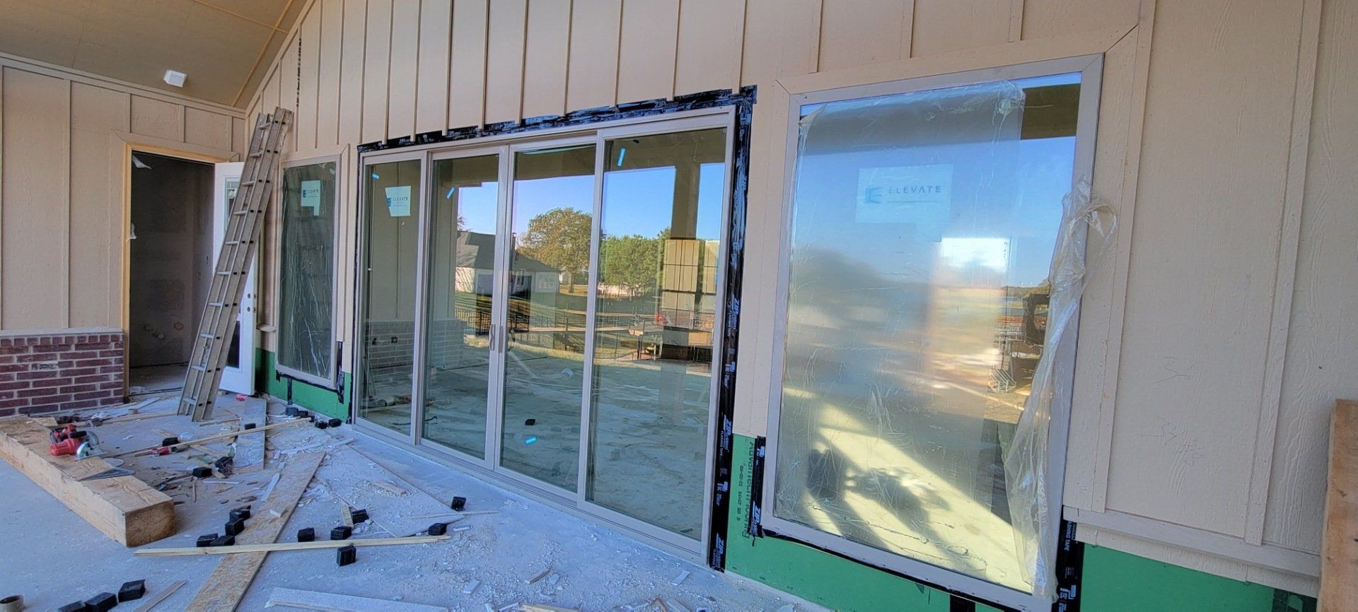 Construction site with large glass storefront windows installed along a beige exterior wall.