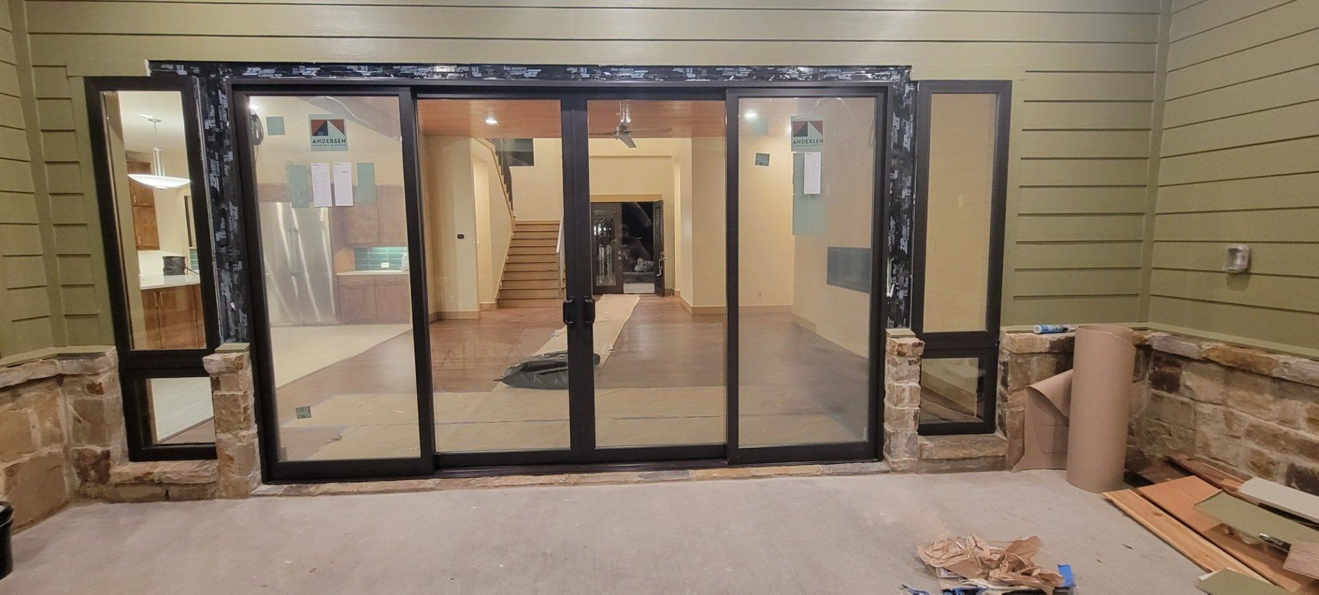 Glass storefront entry under construction in a beige building, with open doorway and tools on the ground.