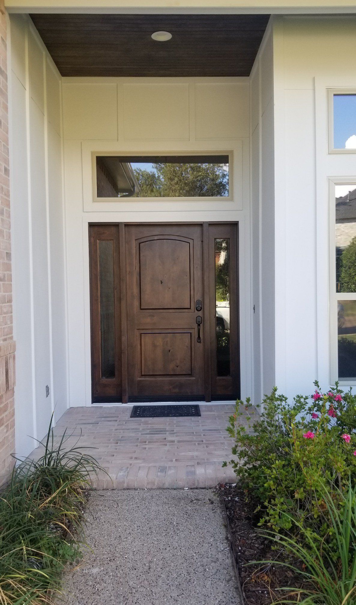 Front entrance with dark wooden double doors, white trim, and a small garden path leading up to it