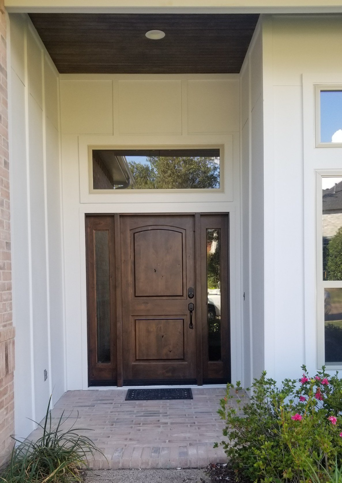 Front entrance with a wooden door, white siding, and small transom window above steps.