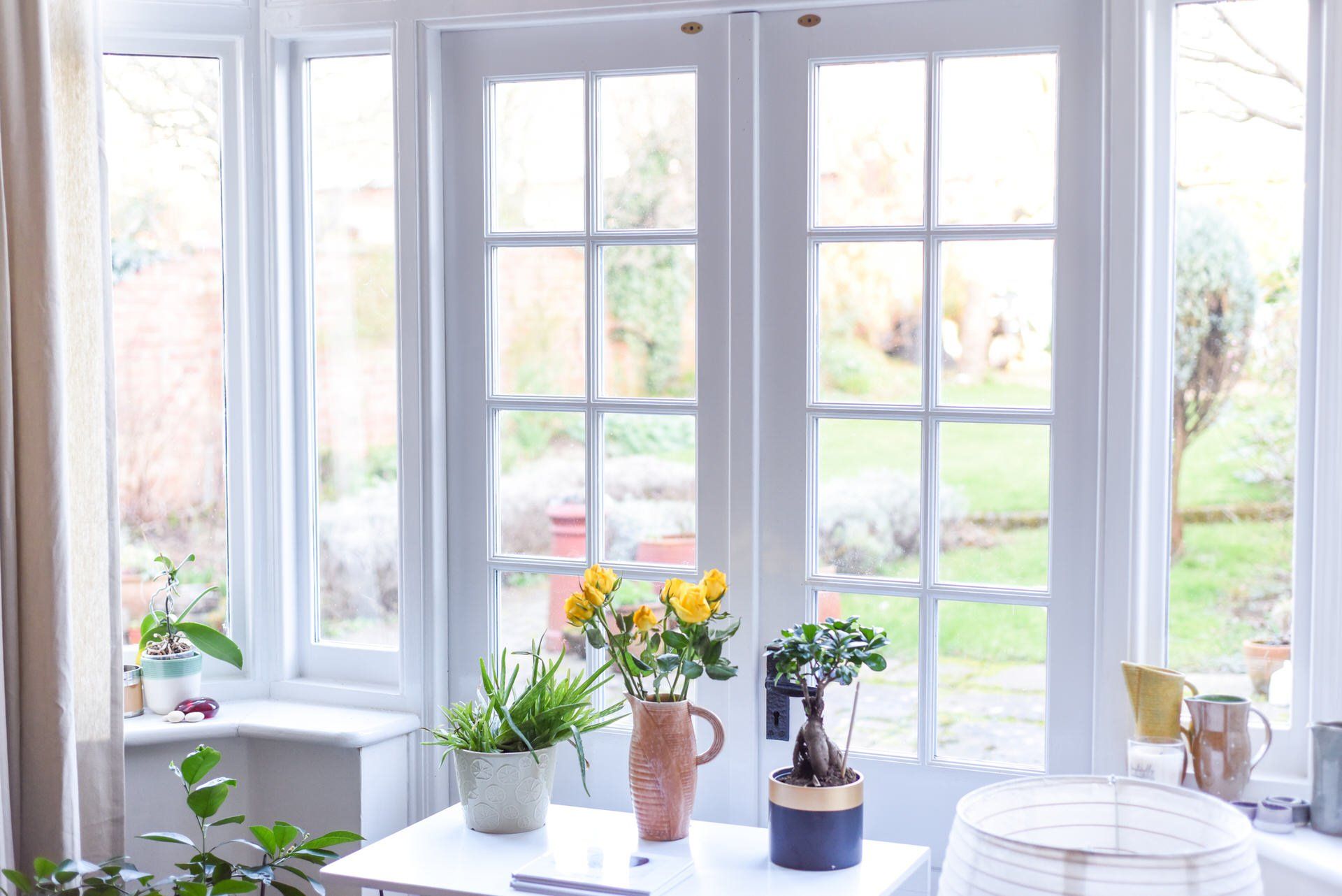 Bright sunroom window with potted plants and flowers on the sill