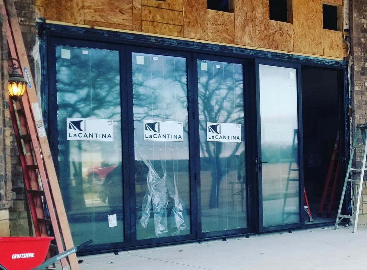 Glass storefront doors under construction with white signs and exposed wood framing above