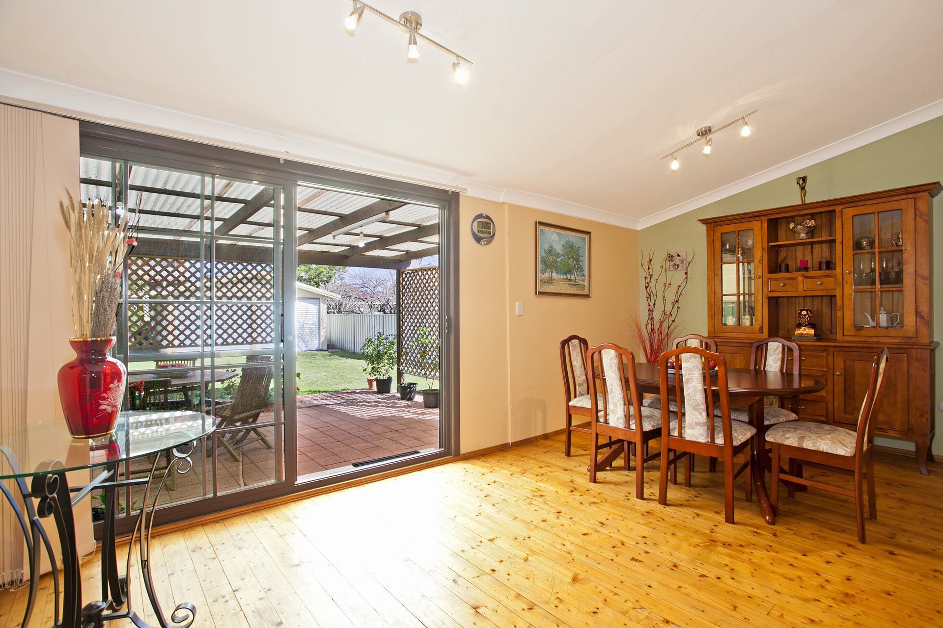Bright dining room with wooden table, chairs, cabinet, and sliding glass doors to a patio