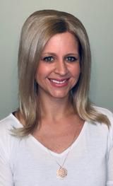 Smiling blonde woman in a white V-neck top against a plain gray background