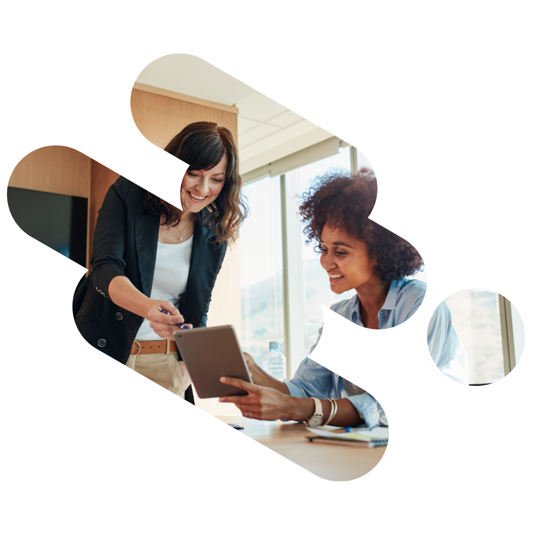 Two women looking at a tablet, one pointing at it. Office setting.