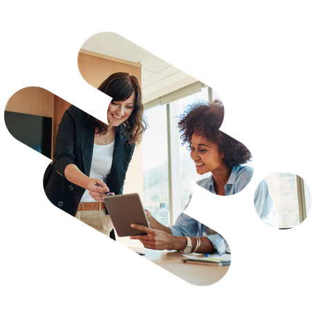 Two women looking at a tablet, one pointing at it. Office setting.