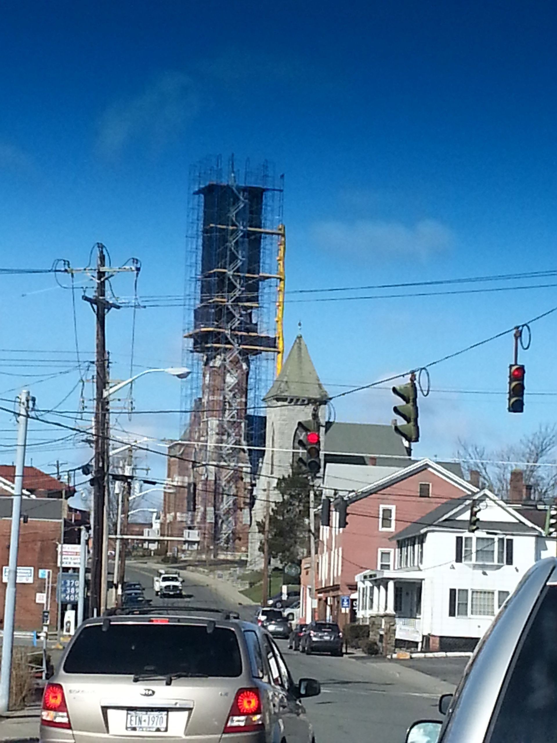 Metal scaffolding against a blue sky. Yellow beams and metal grates make up the work platforms.