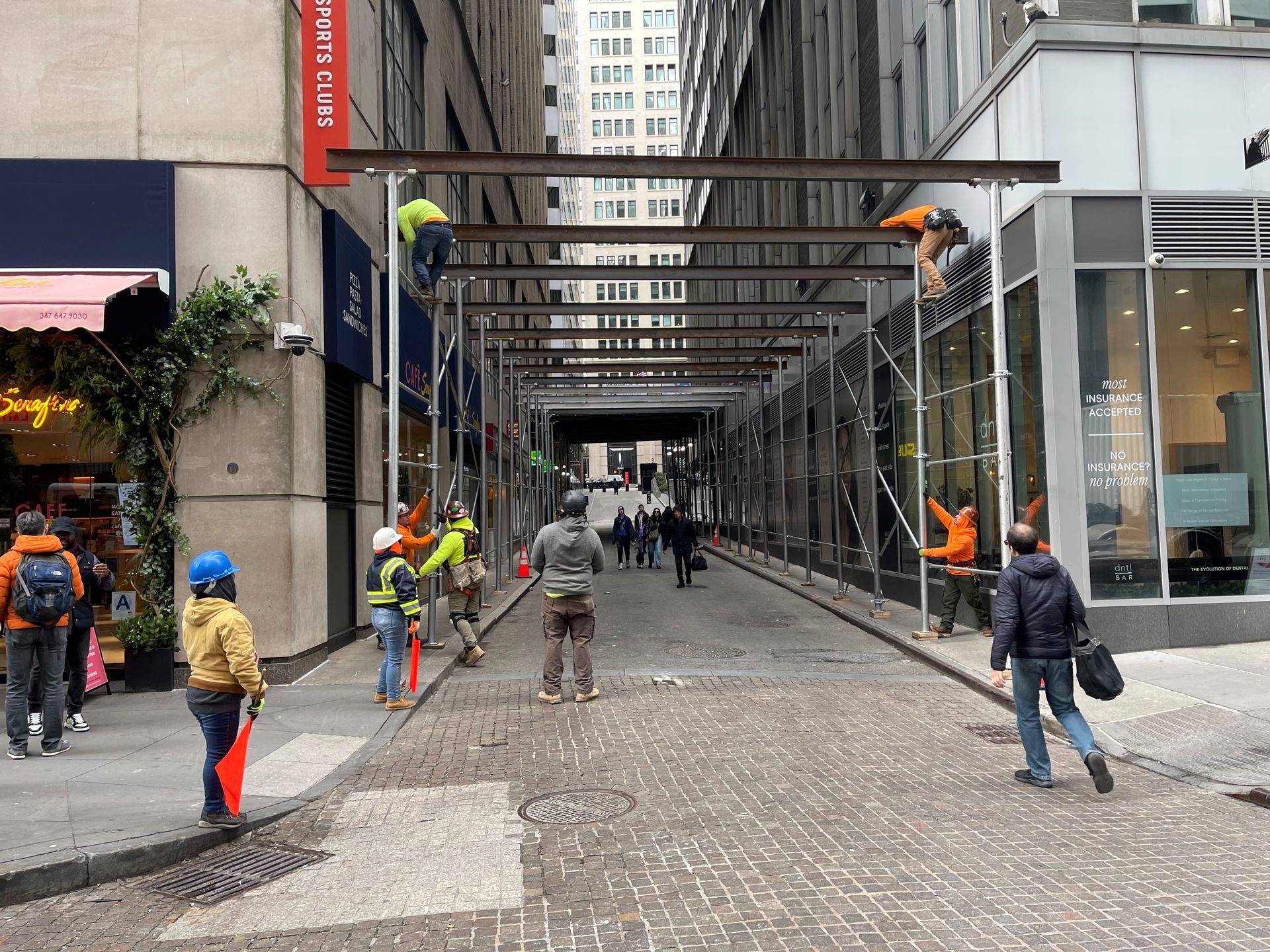 Construction site with concrete pillars, metal scaffolding, and wooden beams in various stages of assembly.